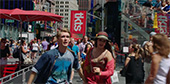 Still image of Charlie (Harry Jarvis) and Barlow (Juliet Doherty) run through Times Square.