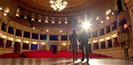 Still image of Barlow (Juliet Doherty) and Charlie (Harry Jarvis) stand on the empty stage.